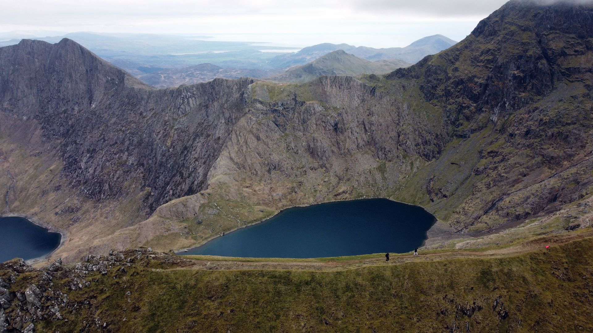 Mountain landscape with two dark blue alpine lakes in a rocky valley under a hazy sky