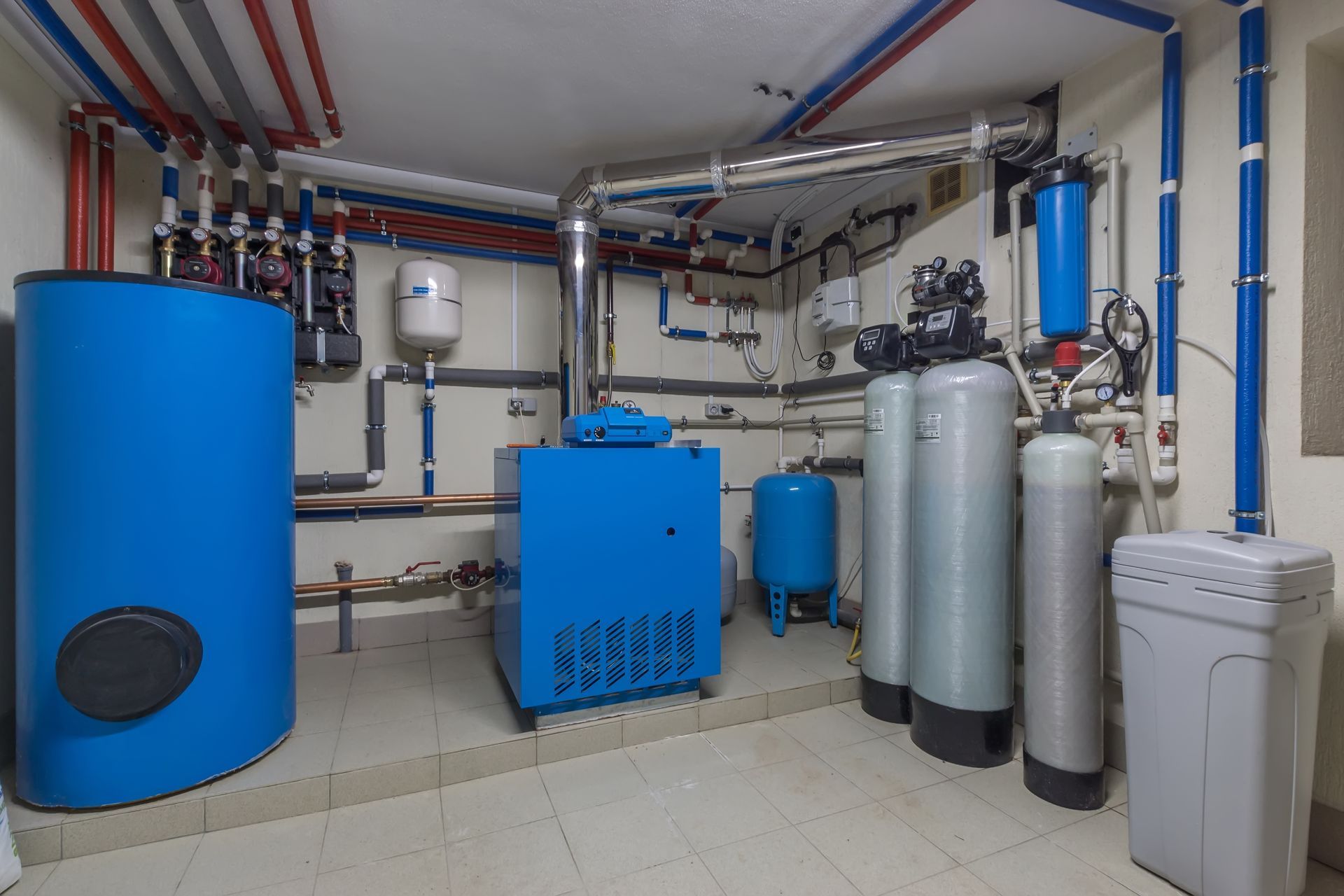 Basement water softener and filtration tanks with plumbing and residential gas water heater systems. Basement water softener and filtration tanks with plumbing and residential gas water heater systems.