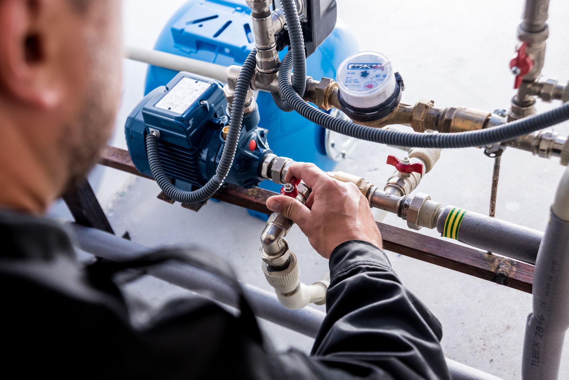 Detailed view of a residential water pump repair showing pipes, pressure gauge, and motor setup. Detailed view of a residential water pump repair showing pipes, pressure gauge, and motor setup.