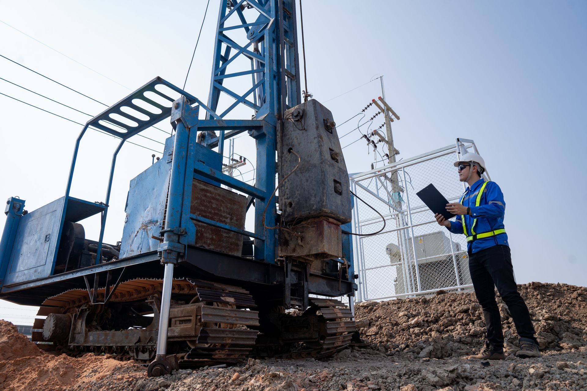 A construction worker is standing in front of a machine on a construction site. A construction worker is standing in front of a machine on a construction site.