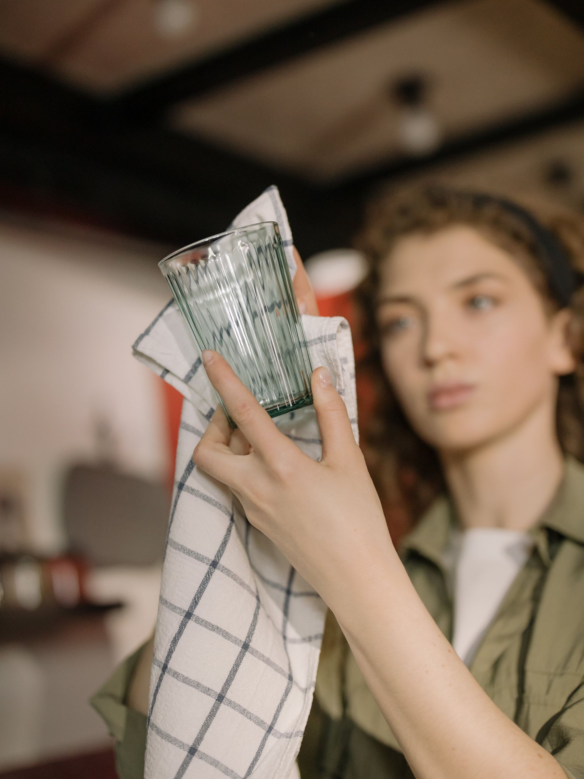 A woman is cleaning a glass with a towel.