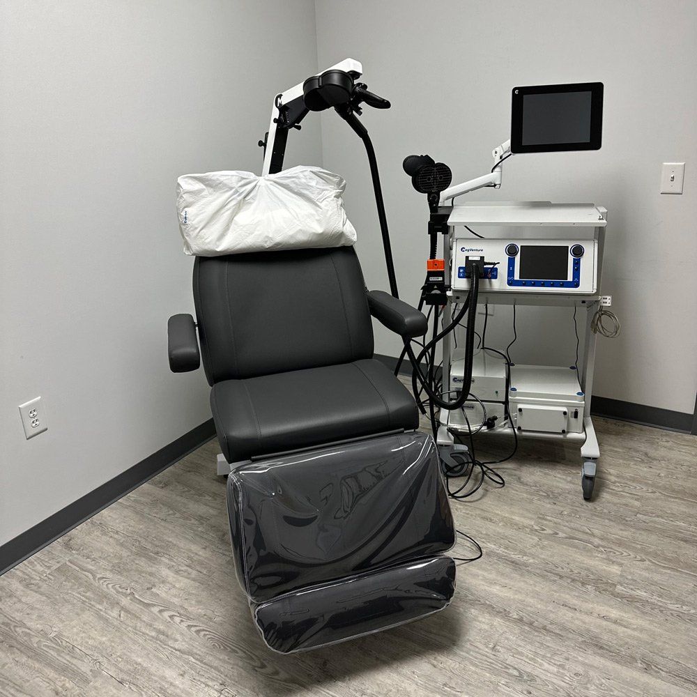 A black chair is sitting in a room next to a machine.