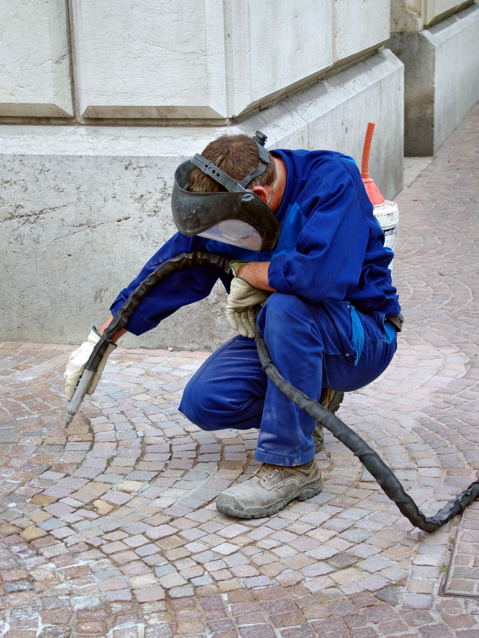 Un homme en combinaison de protection pulvérise une pièce avec un pulvérisateur.