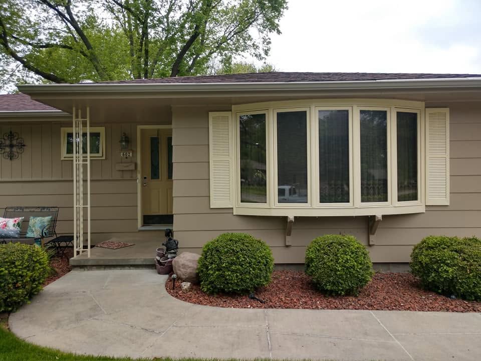 Single-story beige house with a bay window, front porch, and curved concrete walkway