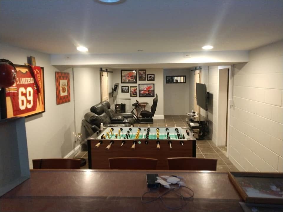 Finished basement with a foosball table, couch, and framed sports jerseys on the wall.