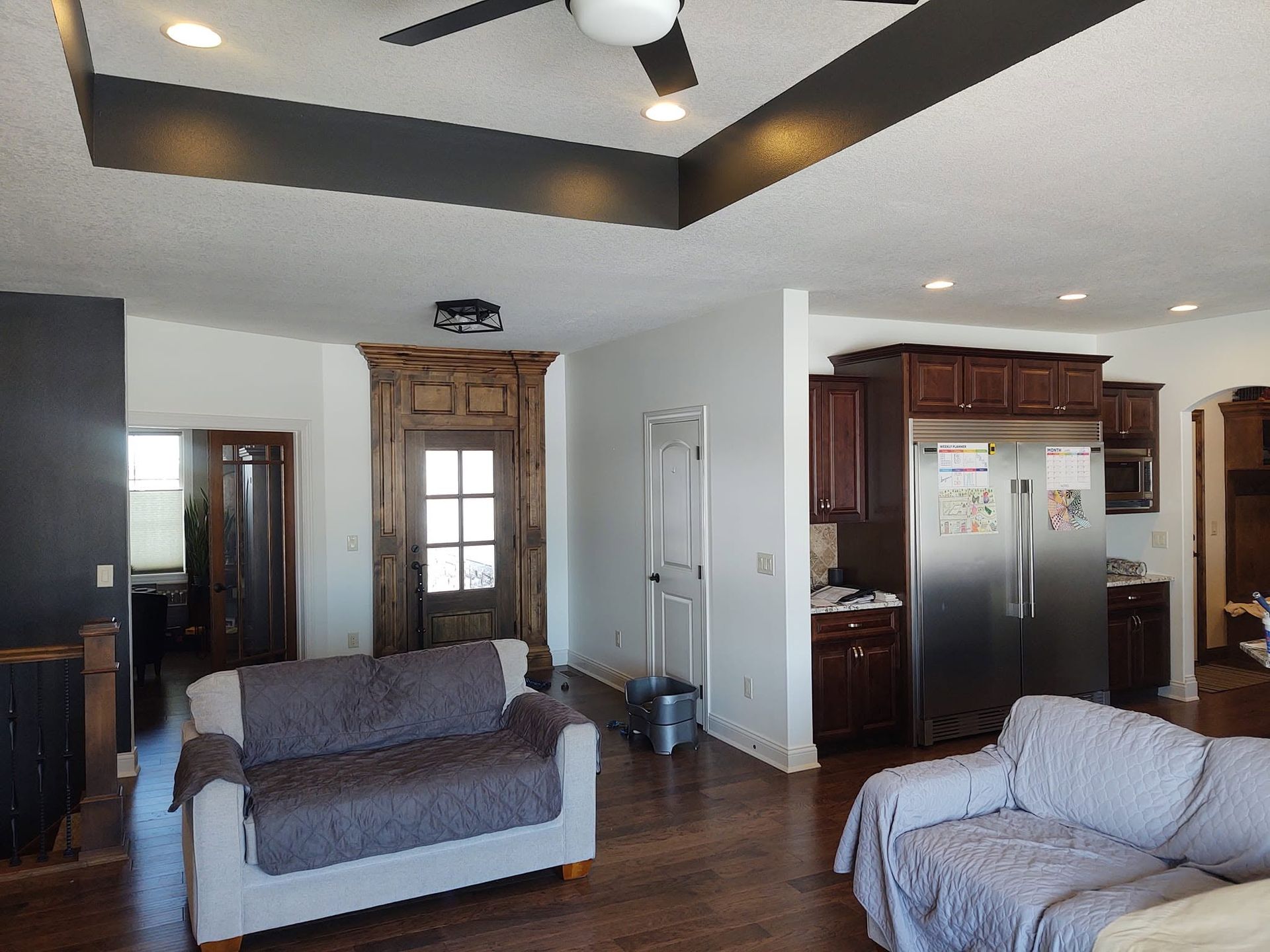 Living room with gray sofas, wood floors, and a kitchen area in the background