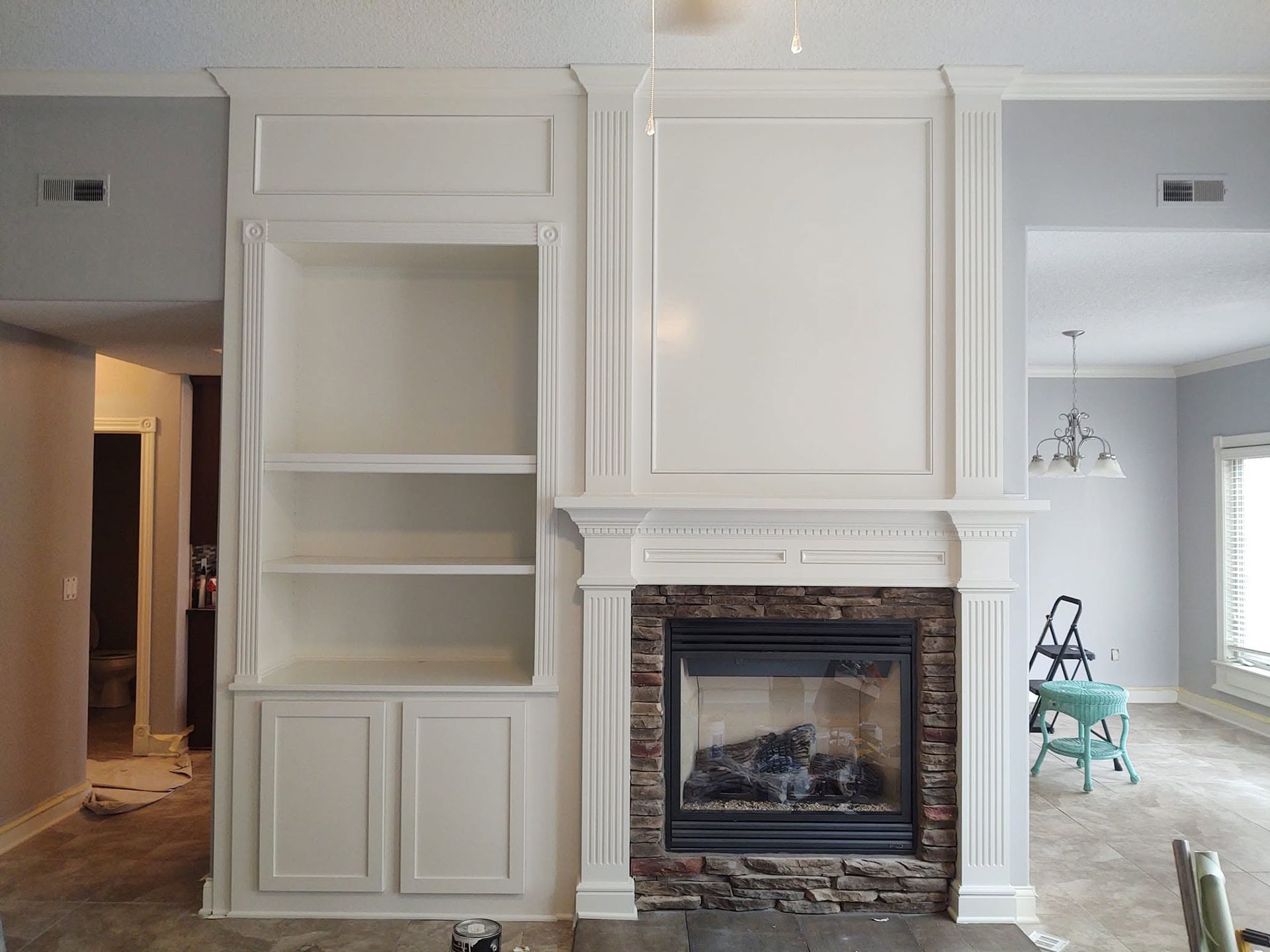 Built-in shelves and fireplace in a bright, empty living room with white trim and marble surround