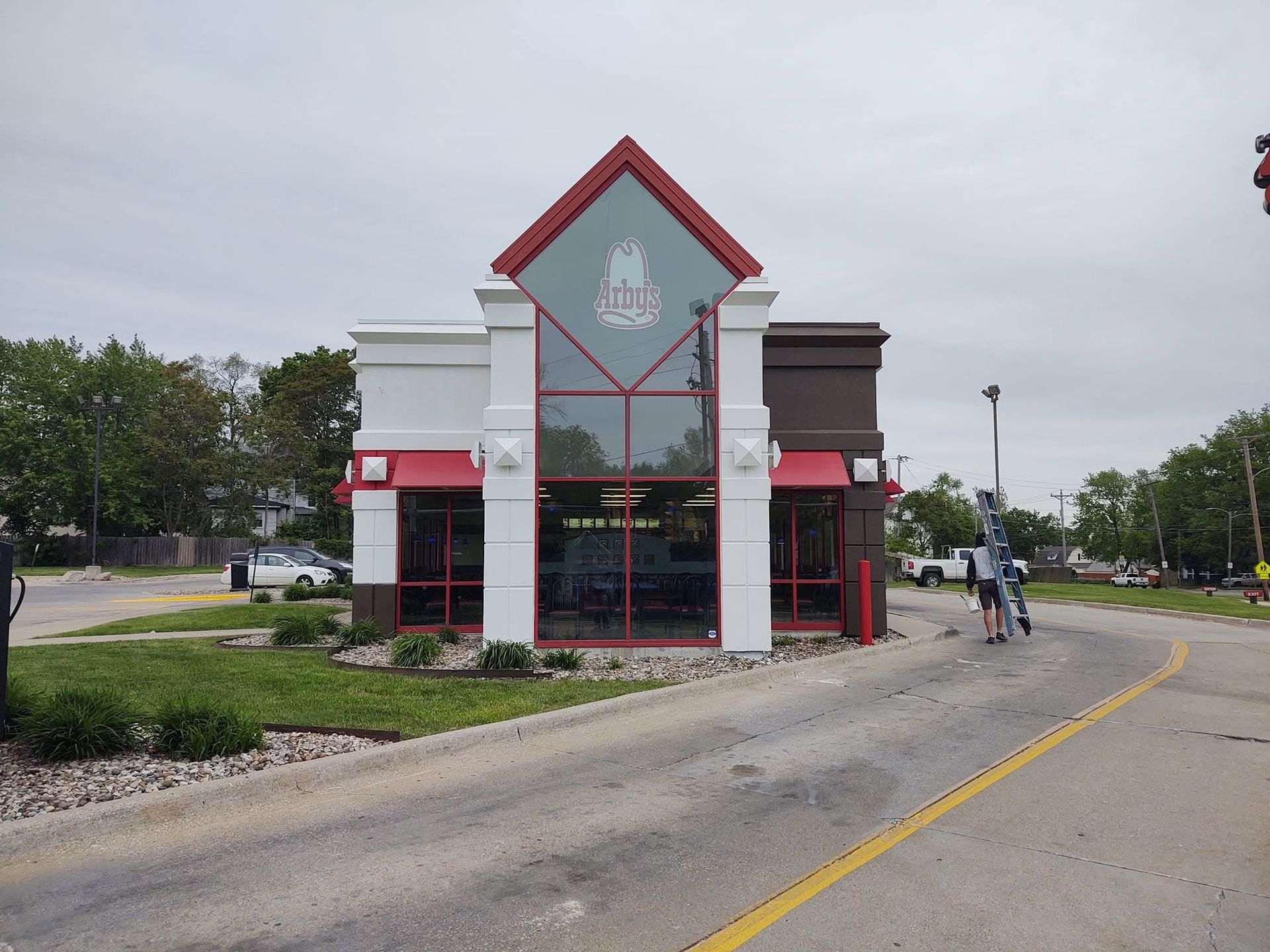 Small roadside storefront with red trim and a central glass facade beside a curved street.