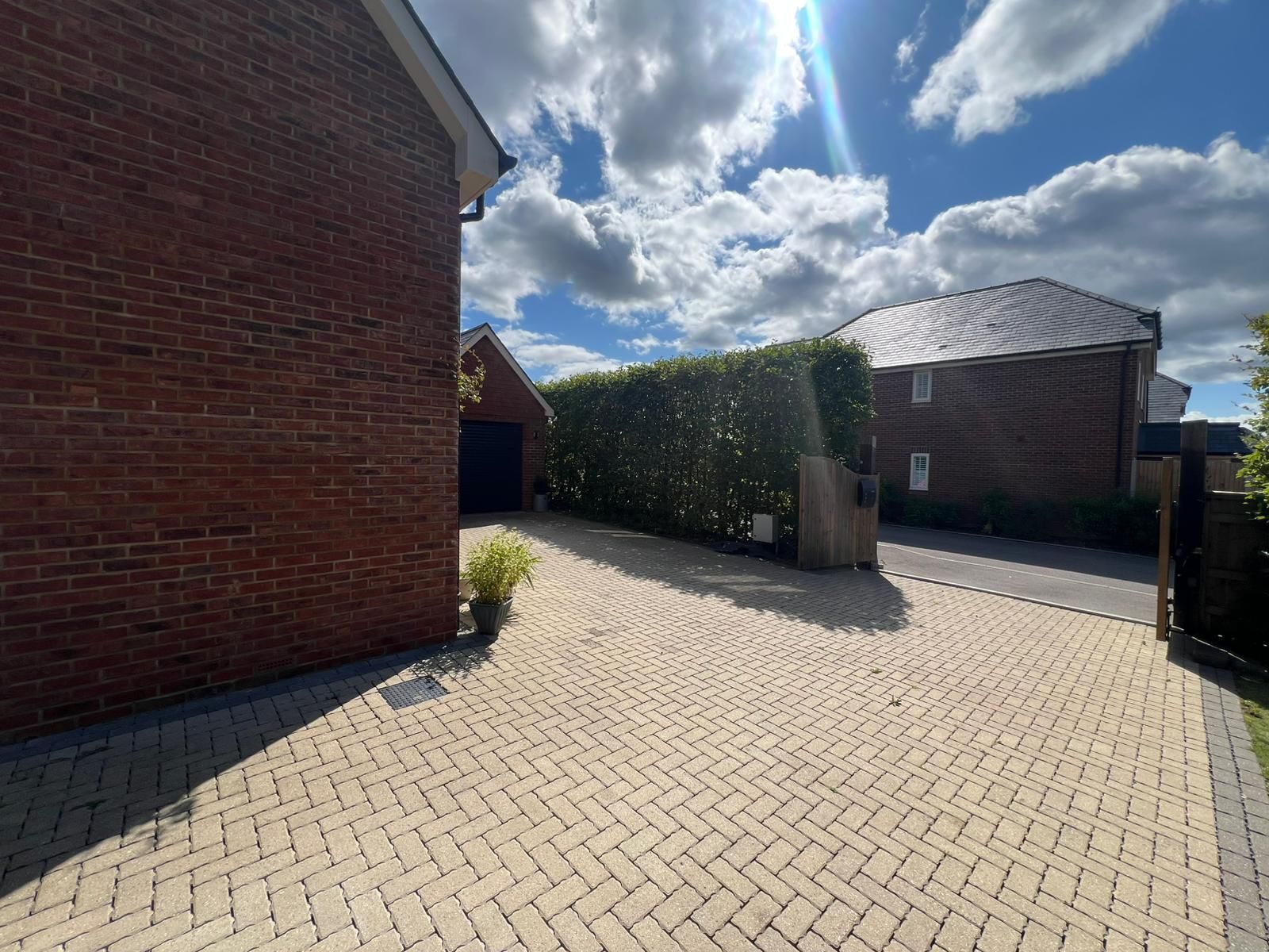 wraparound driveway with house on the left with hedge row in front