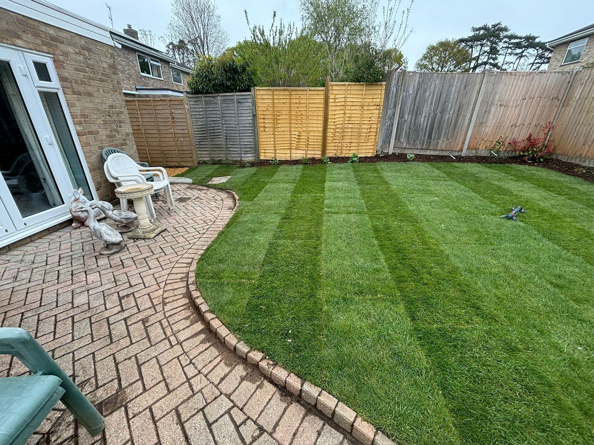 New fence panels behind freshly cut grass and patio