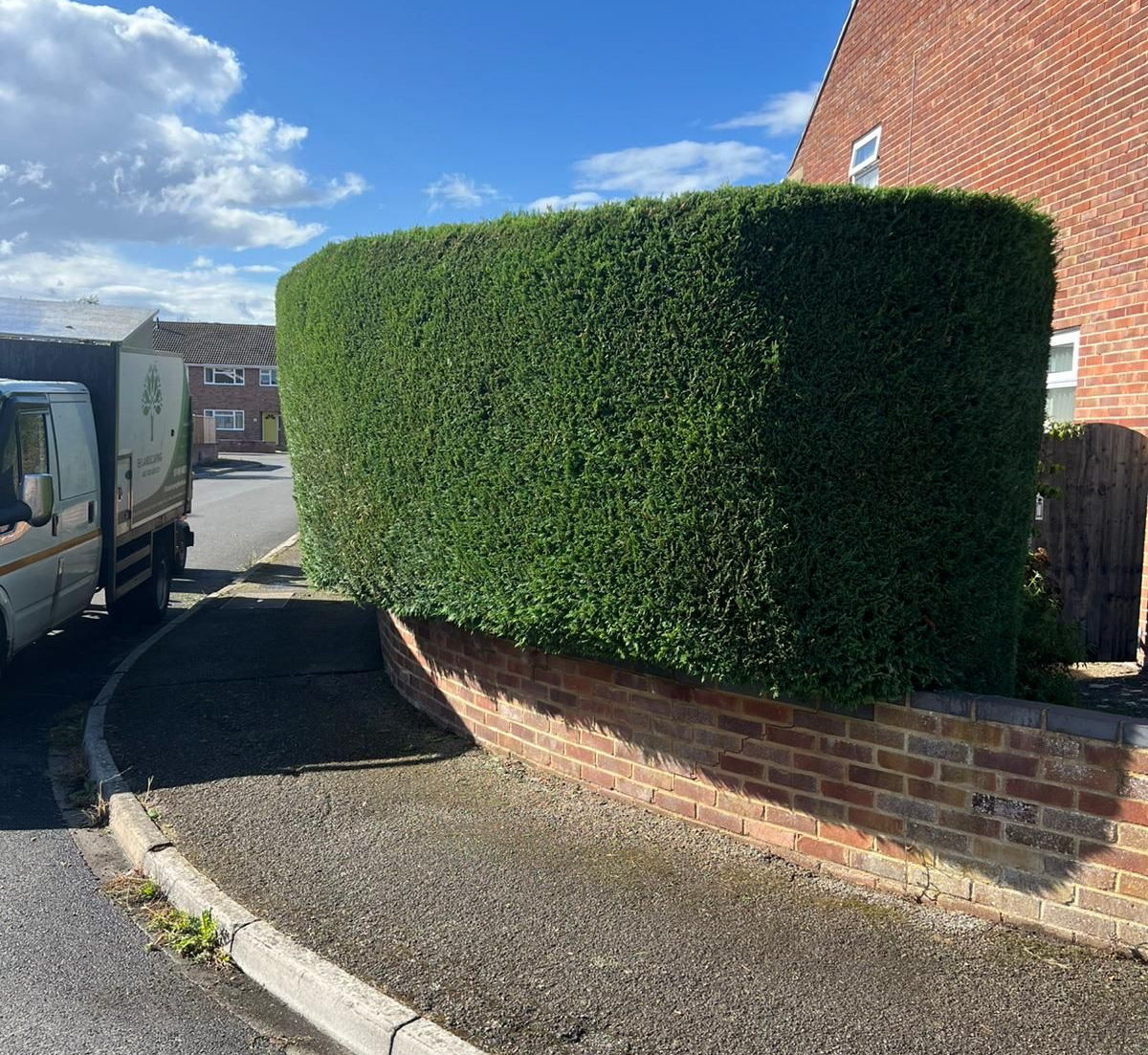 Hedge neatly trimmed with path and truck to the left