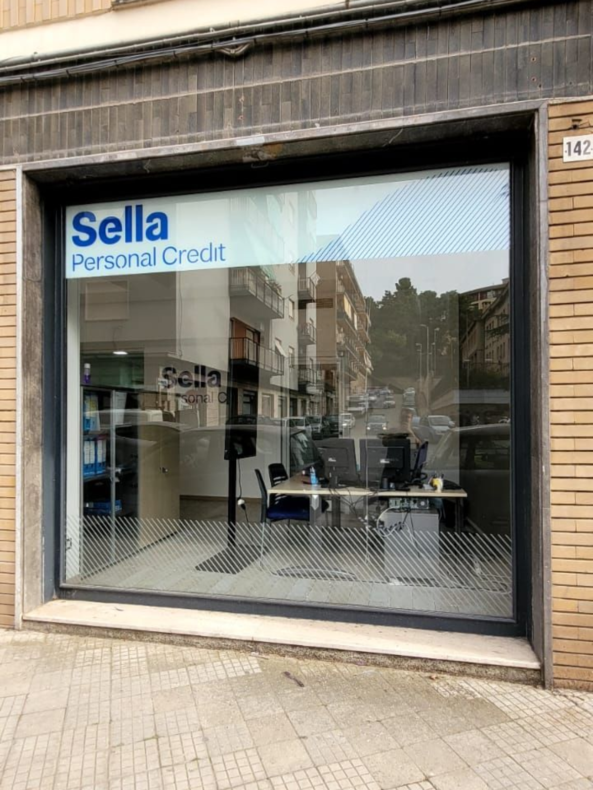 Facciata di un ufficio della Sella Personal Credit con vetrina e facciata in mattoni.