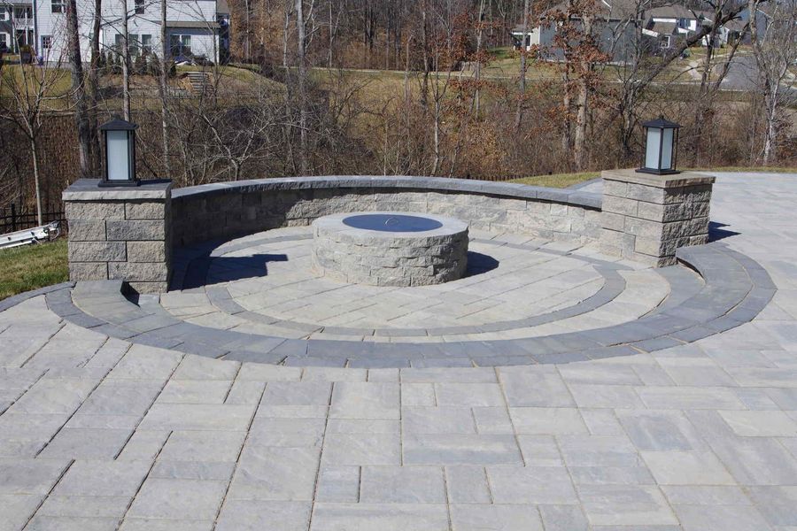 Stone memorial fountain with curved benches and a circular paved plaza outdoors