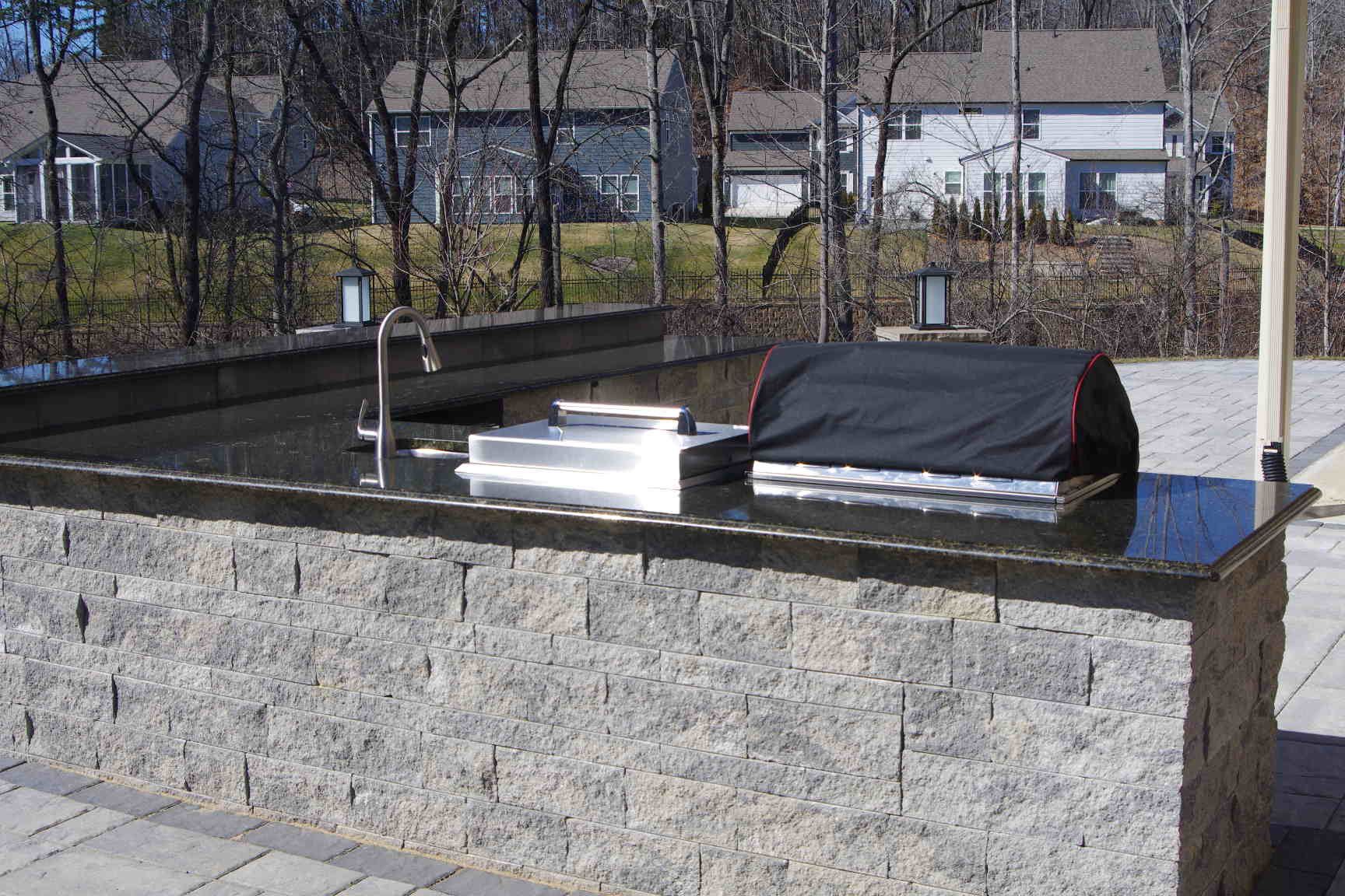 Stone outdoor altar with a black-covered tomb and white floral arrangement in a cemetery