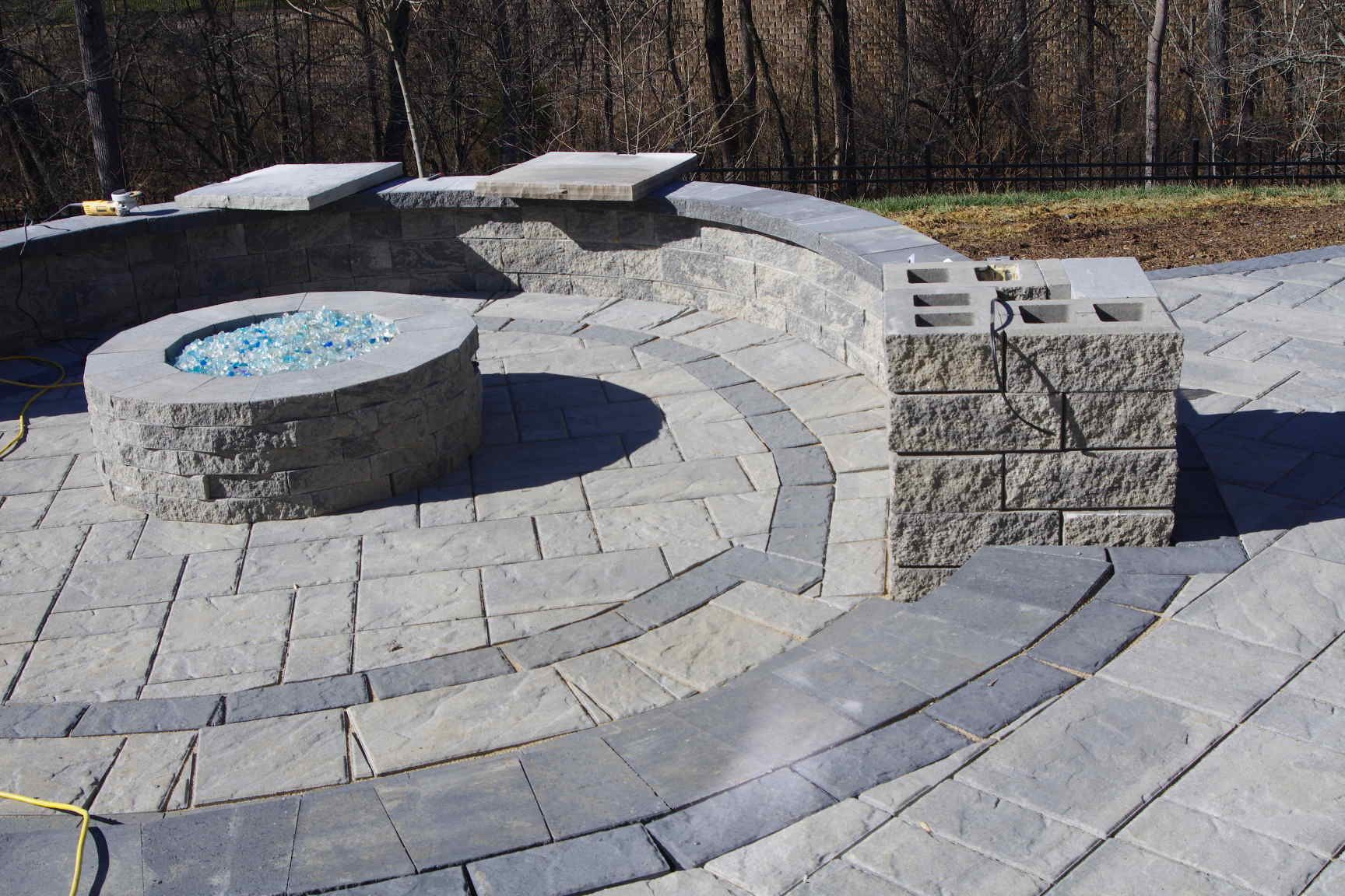 Curved stone amphitheater seating around a circular fire pit in an outdoor park