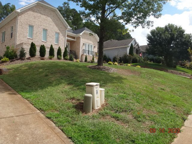 Suburban house with a sloped lawn, sidewalk, and utility boxes in the front yard