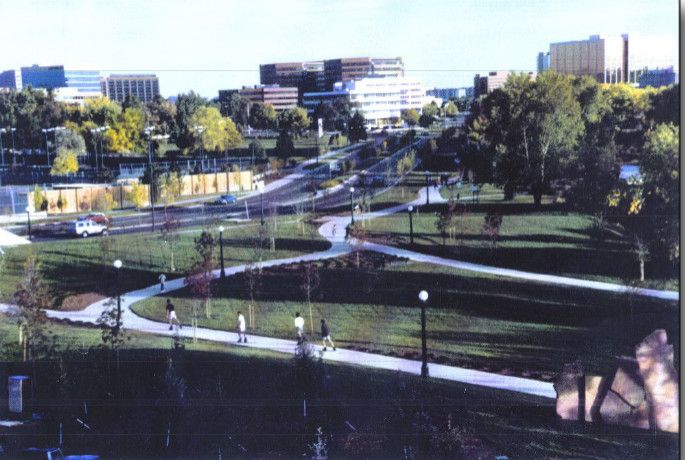 Curving pedestrian paths through a green park with trees, lampposts, and city buildings in the background