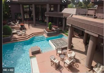 Luxury courtyard with turquoise pool, lounge chairs, and covered patio seating