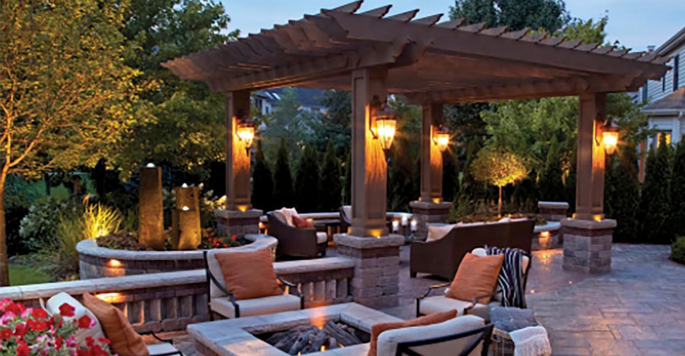 Outdoor patio with pergola, cushioned seating, and warm lantern lighting at dusk