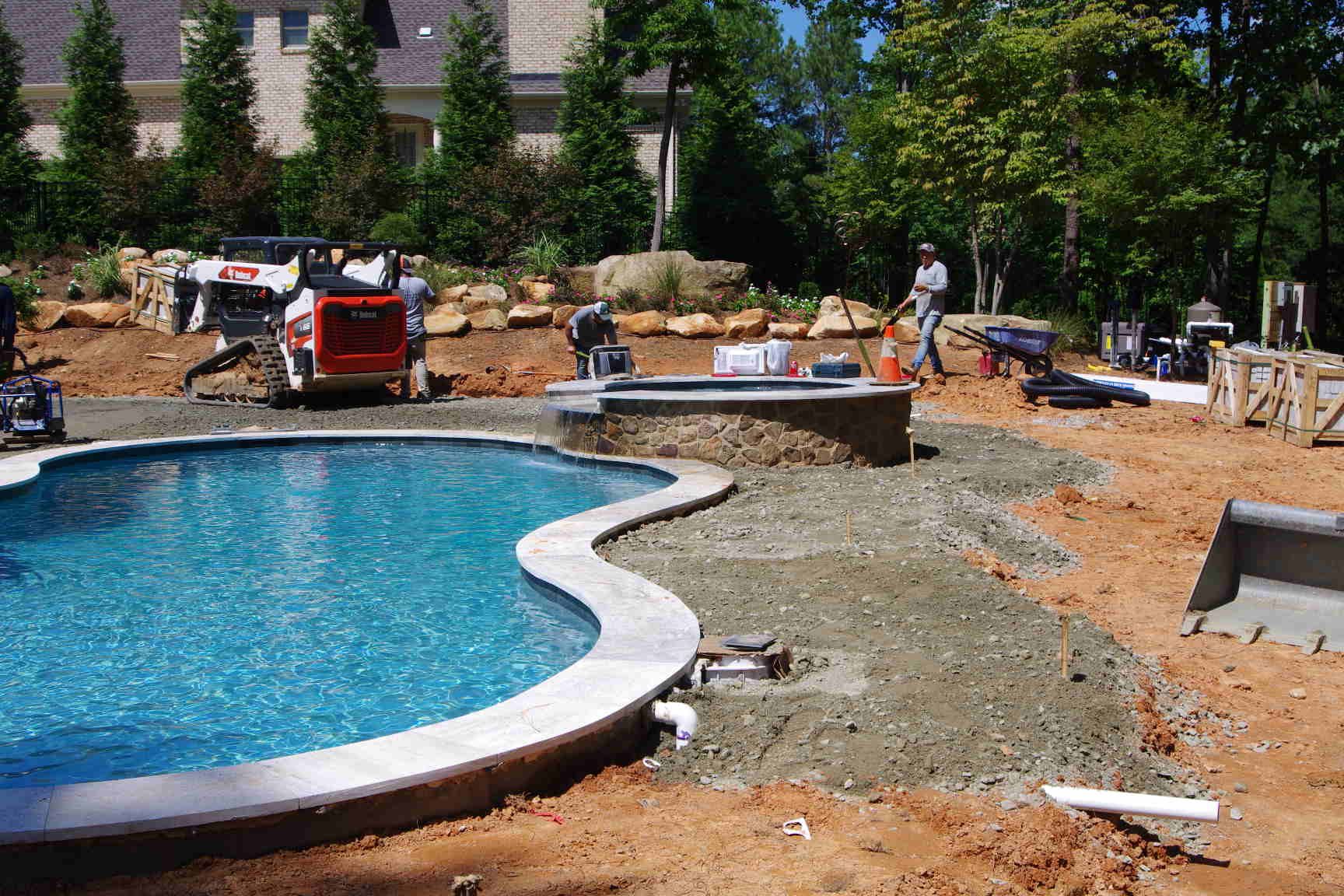 Partially built stone wall with two gray pillars on a paved patio