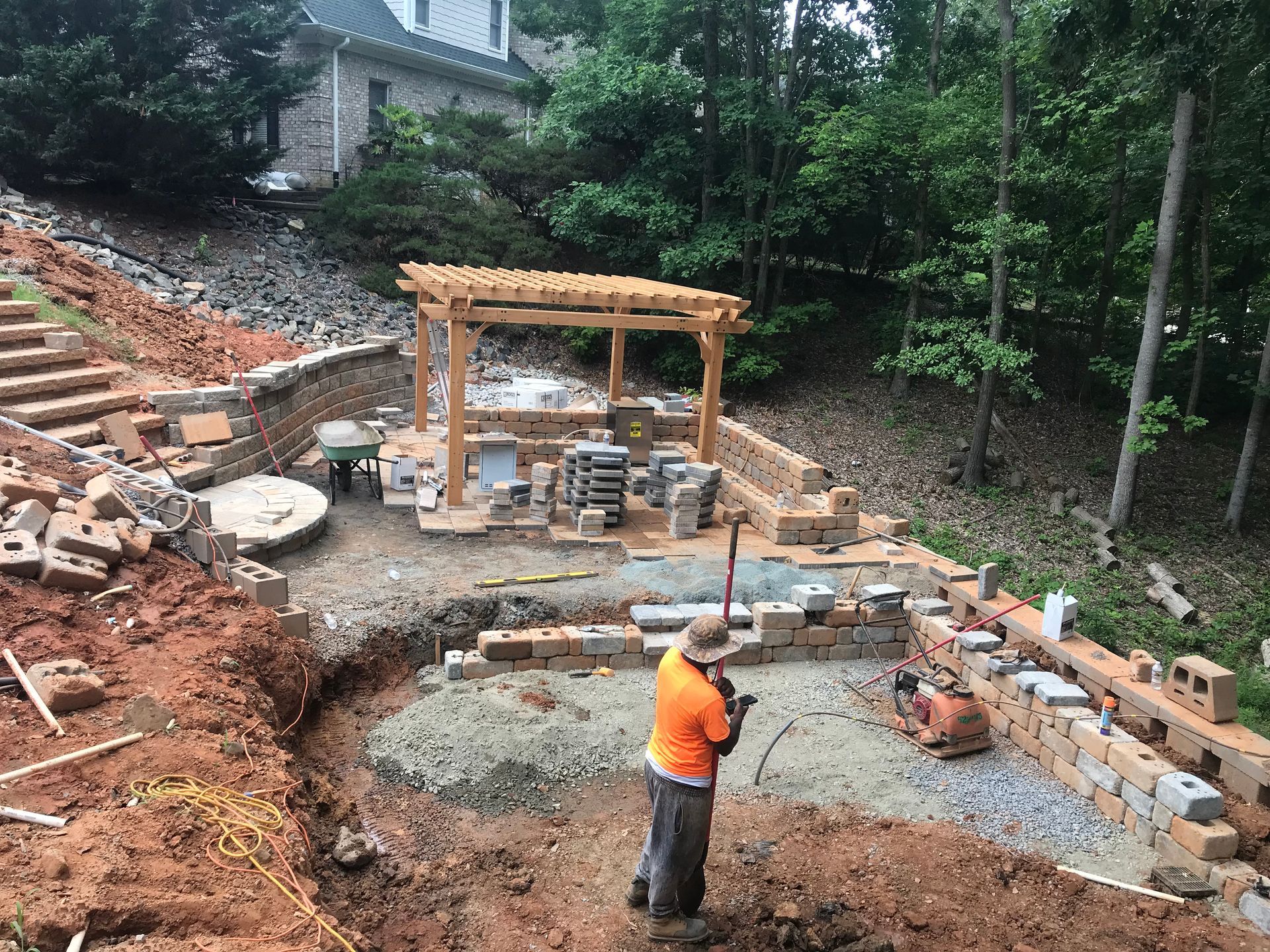 Wooden pergola over a stone patio with outdoor chairs and tables in a garden setting