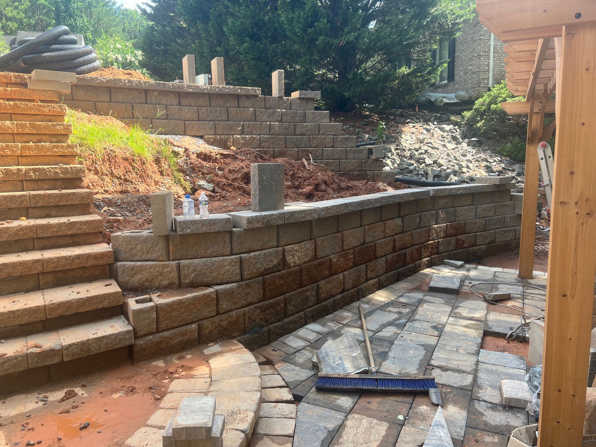 Stone patio beside landscaped garden with curved retaining wall and white gazebo