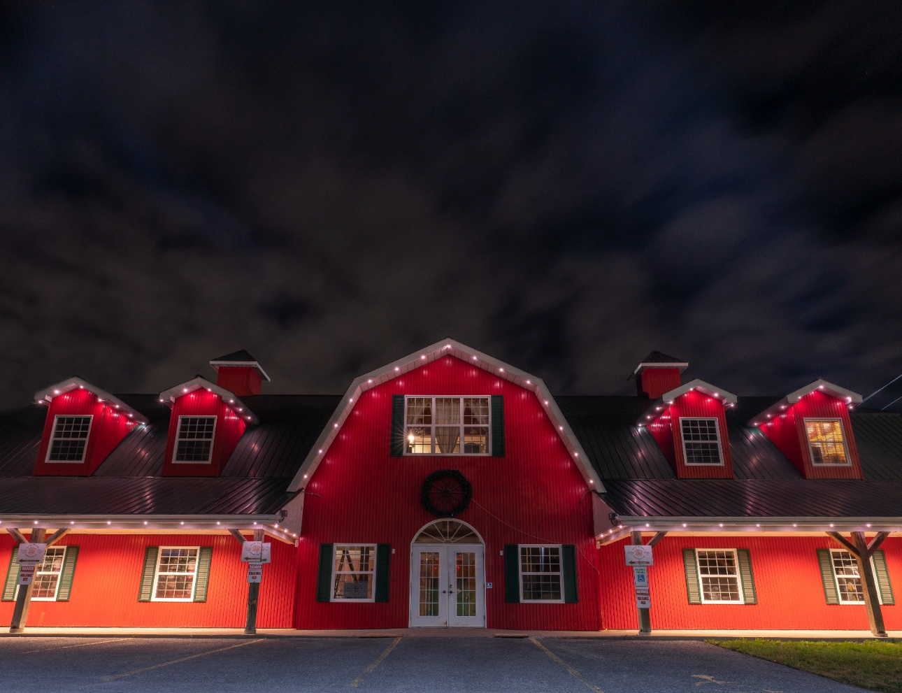 Red barn with Christmas lights against a night sky.