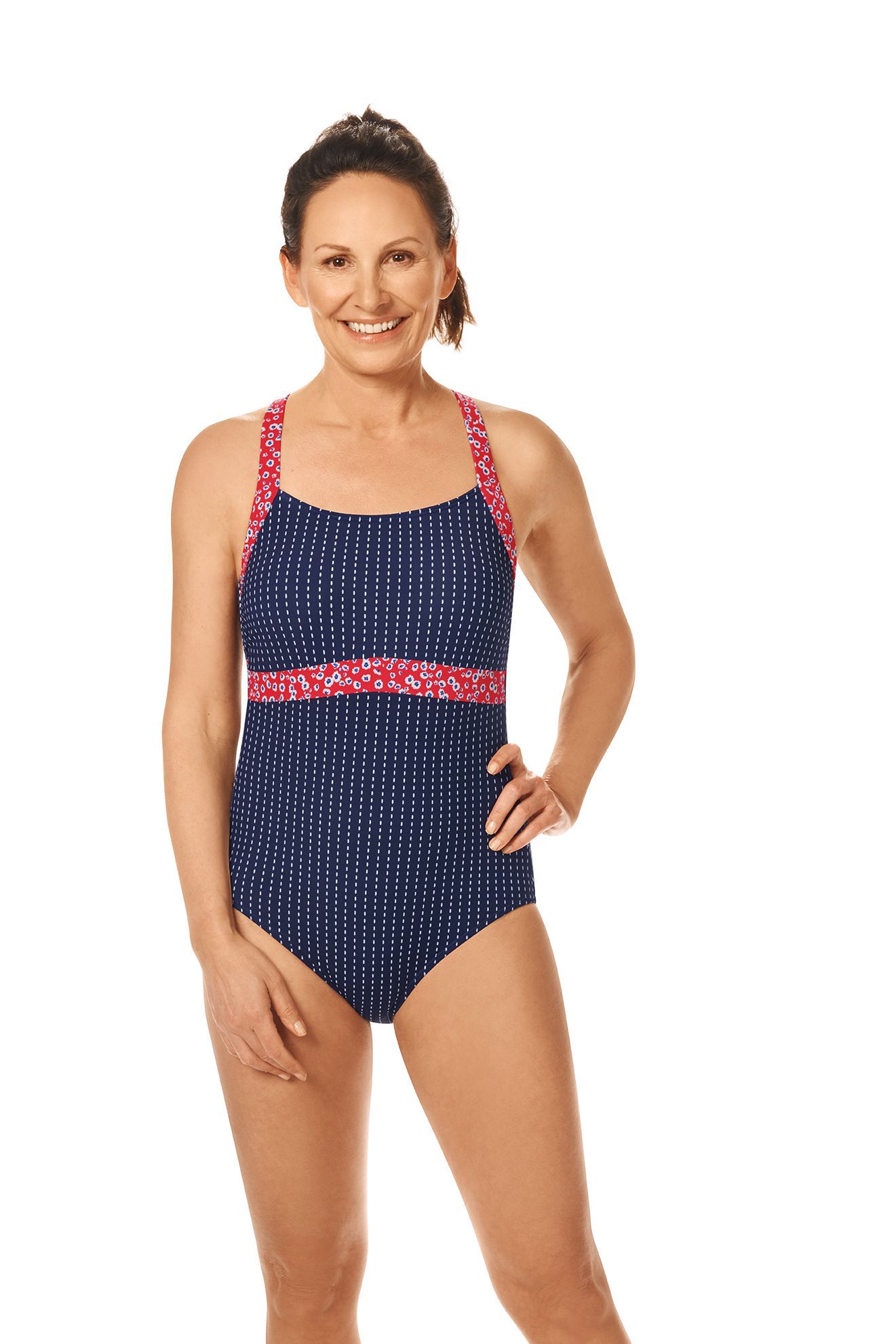 Woman wearing blue and pink patterned swimsuit, smiling, hands on hips.