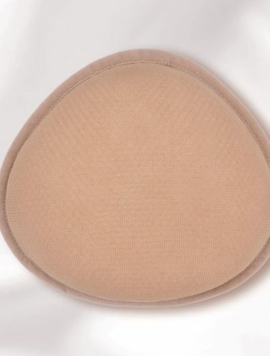 Tan breast form. Tear-drop shaped with a mesh surface and a rounded edge.