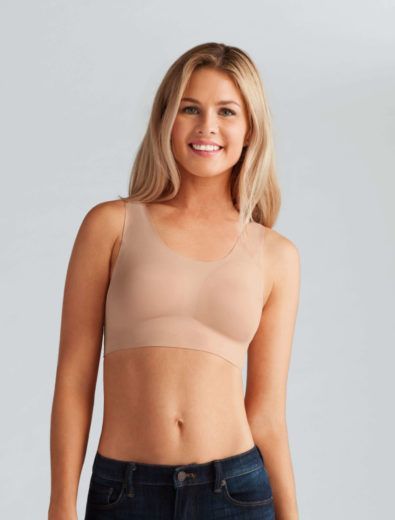 Woman in a nude-colored bra and jeans, smiling.