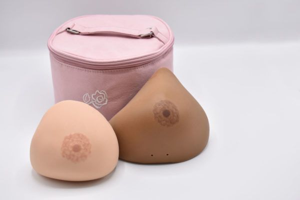 Two breast prostheses of different skin tones with a pink storage case.
