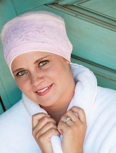 Woman in pink head covering and white robe, smiling.