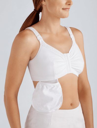 Woman wearing a white, front-closure bra with a pocket. She is facing forward, smiling, with a ponytail.