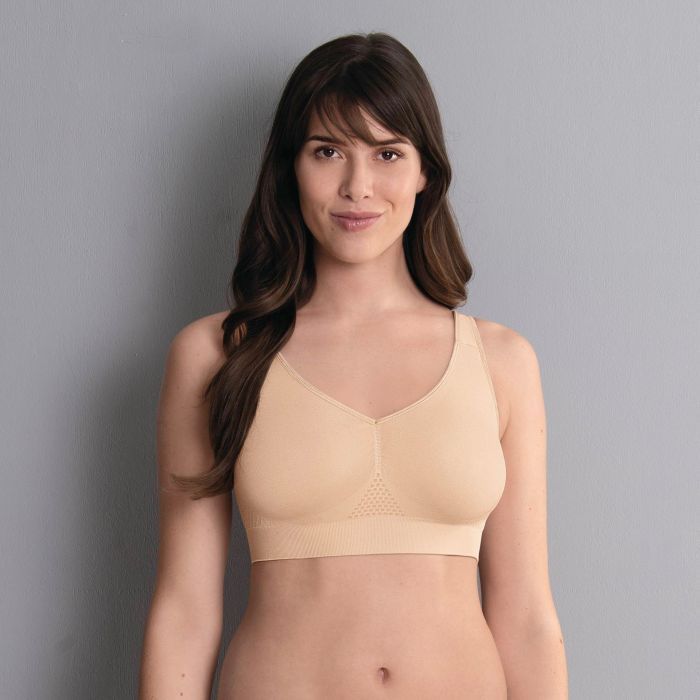 Woman wearing a beige seamless bra, smiling at the camera.