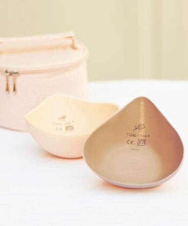 Two teardrop-shaped breast forms, one beige, one pink, next to a matching pink cosmetic bag.