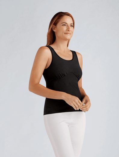 Woman in black tank top and white pants, looking to the side.