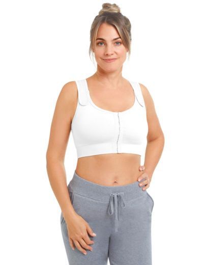 Woman in white compression bra and gray sweatpants, smiling.