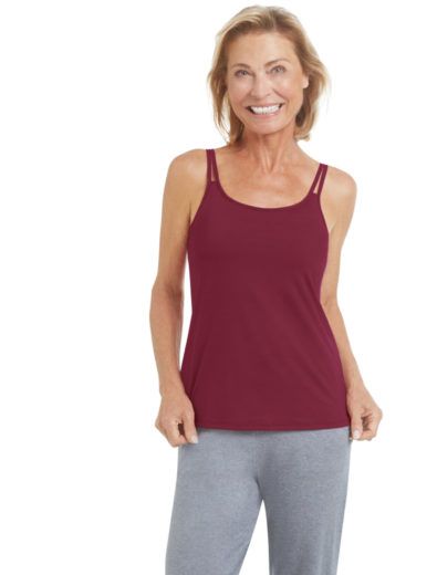 Woman in a burgundy tank top and gray pants, smiling. White background.