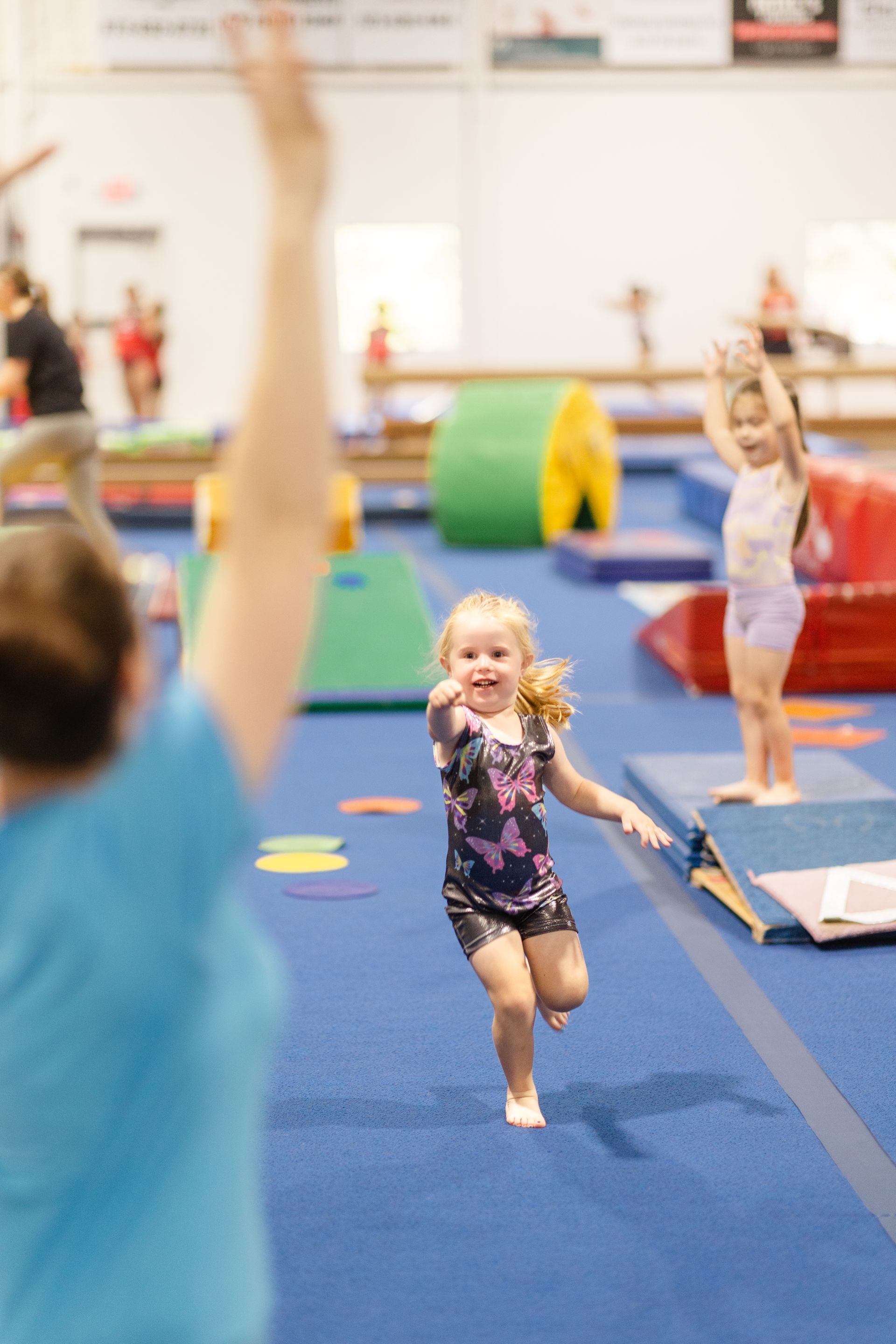 A little girl is running on a balance beam in a gym.
