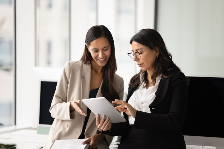 Two professionals reviewing a tablet together in a bright office
