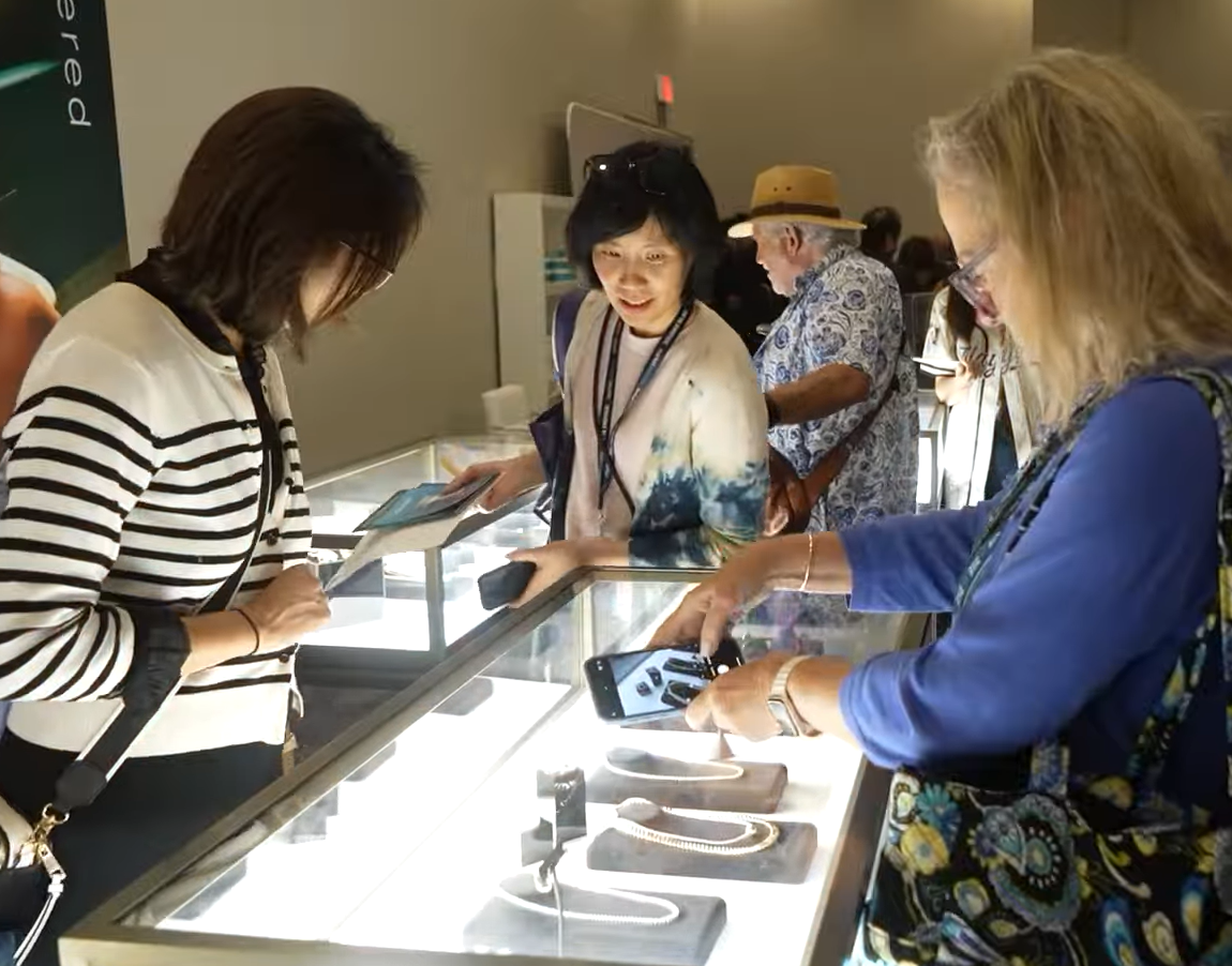 Three people looking at displays in a brightly lit exhibit hall. Professionals working for the community of entrepreneurs.
