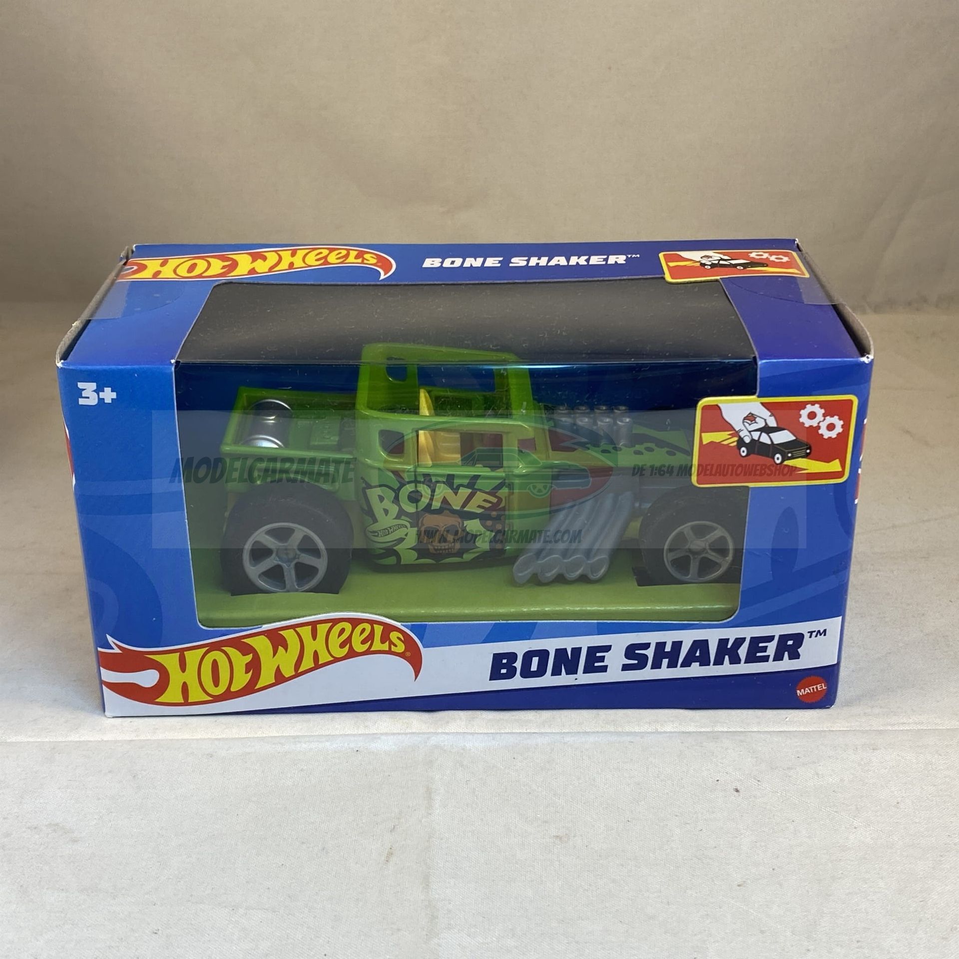 Hot Wheels Bone Shaker speelgoedauto in een blauwe doos. De auto is groen en zwart geverfd.