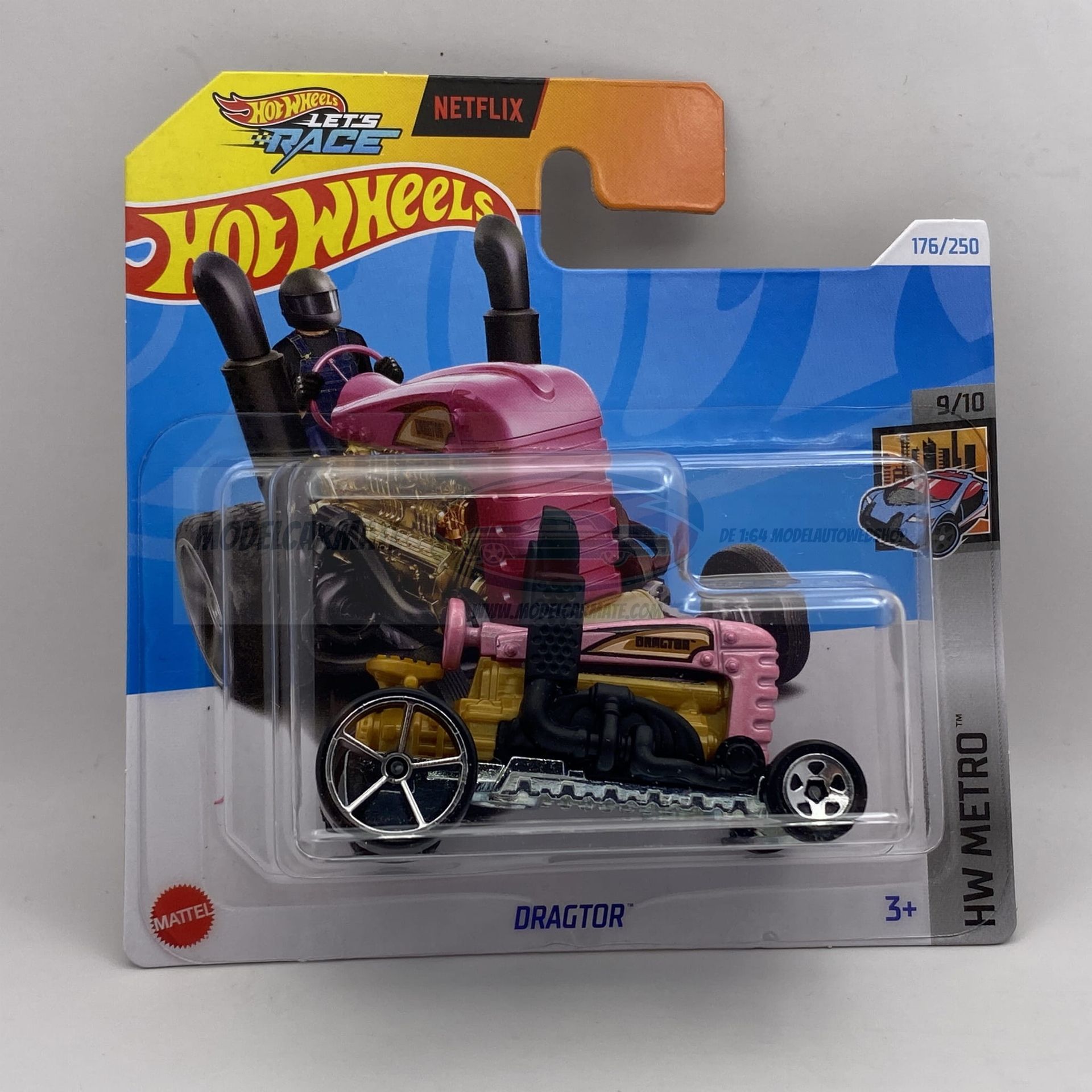 Hot Wheels speelgoedtractor in roze en geel met bestuurder, in de originele verpakking.