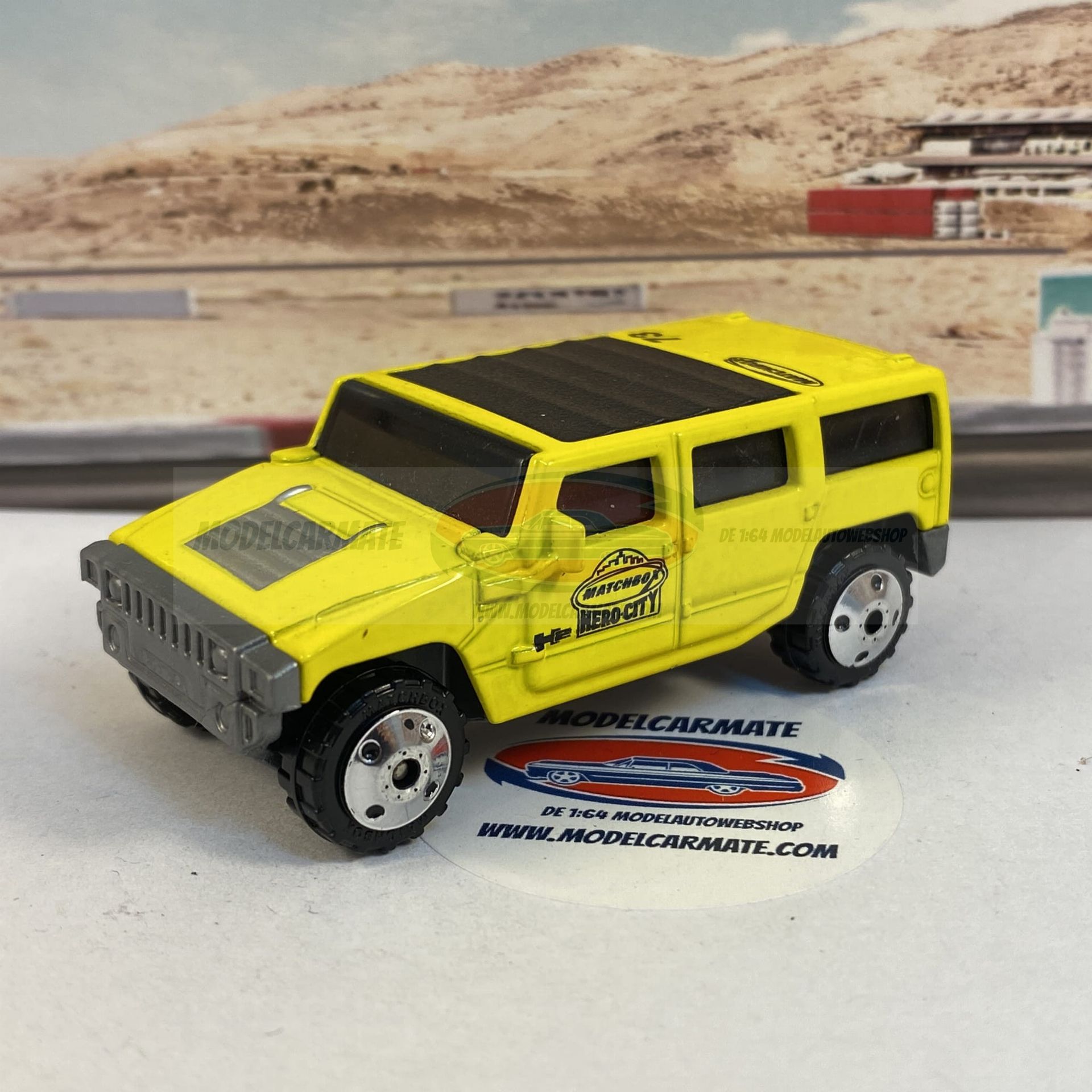 Gele speelgoed-Hummer SUV met zwart dak op een racebaanachtergrond.