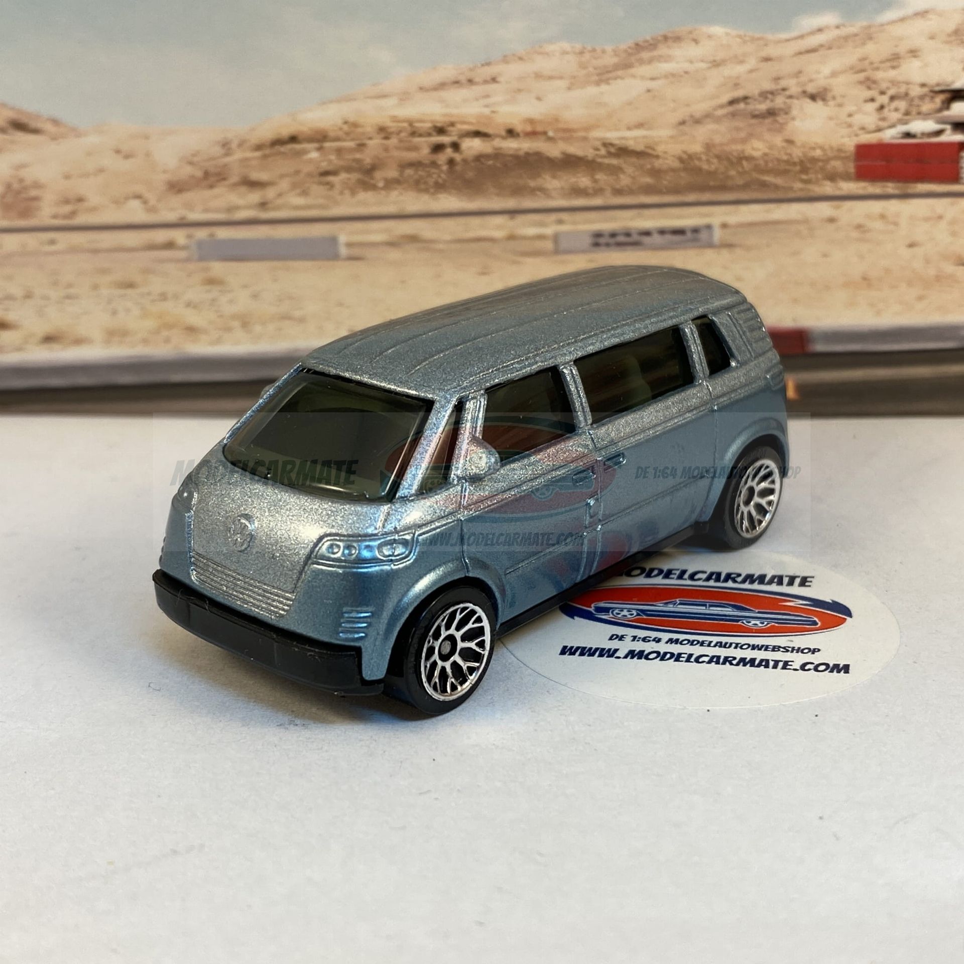 Gegoten metalen lichtblauwe bestelwagen op een witte ondergrond met een wazige buitenachtergrond.