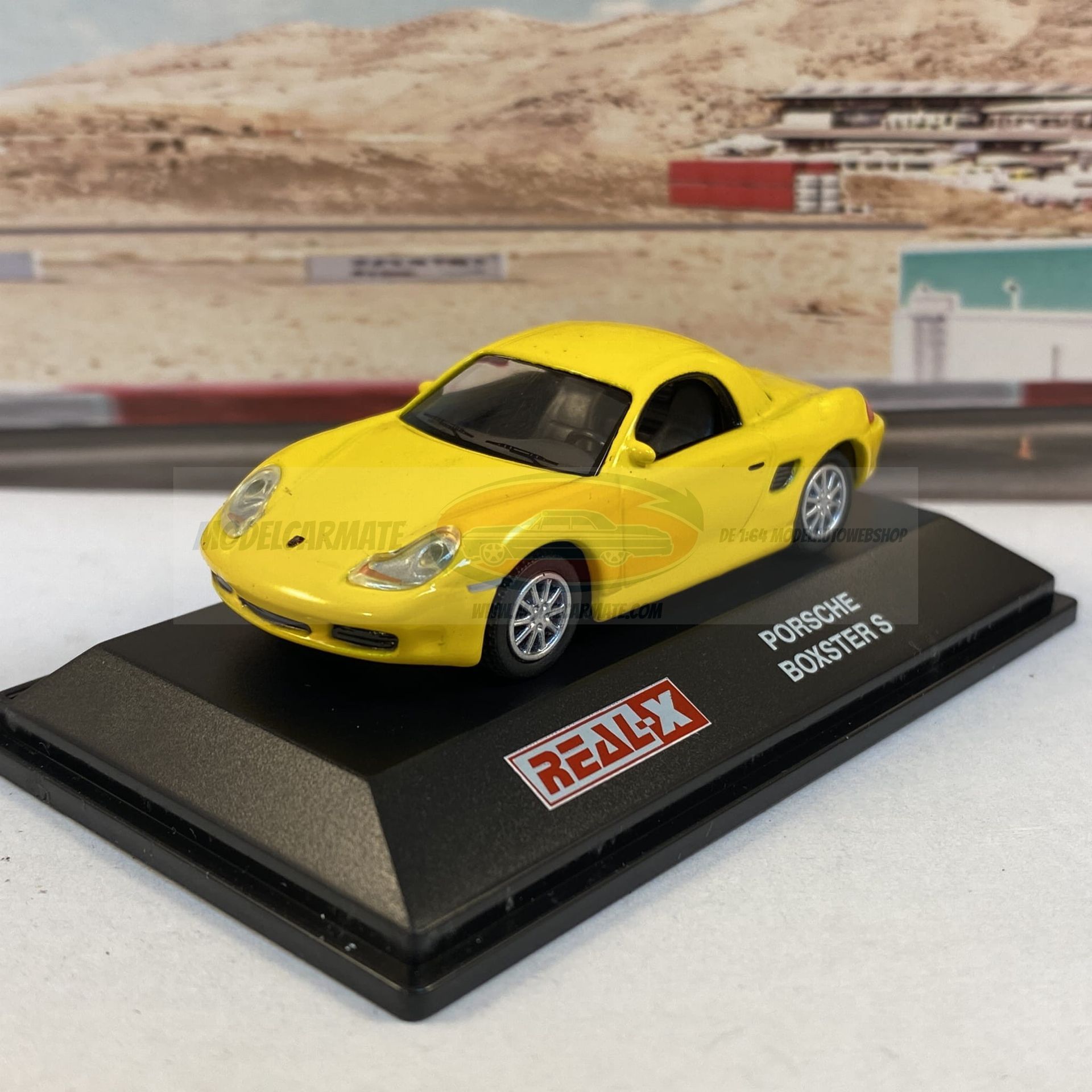 Gele Porsche Boxster S op een zwarte displaystandaard.