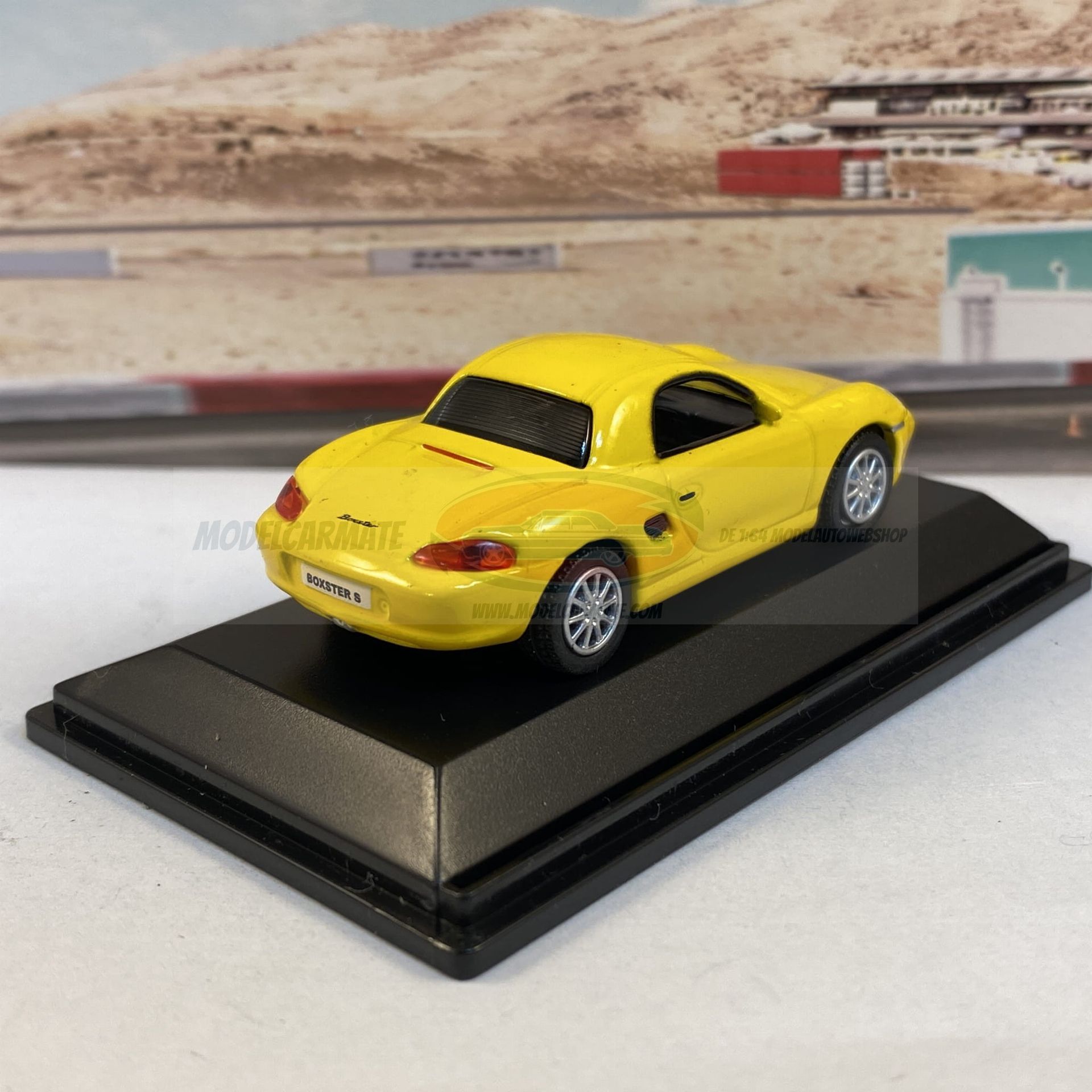 Gele Porsche Boxster S op een zwarte displaystandaard.