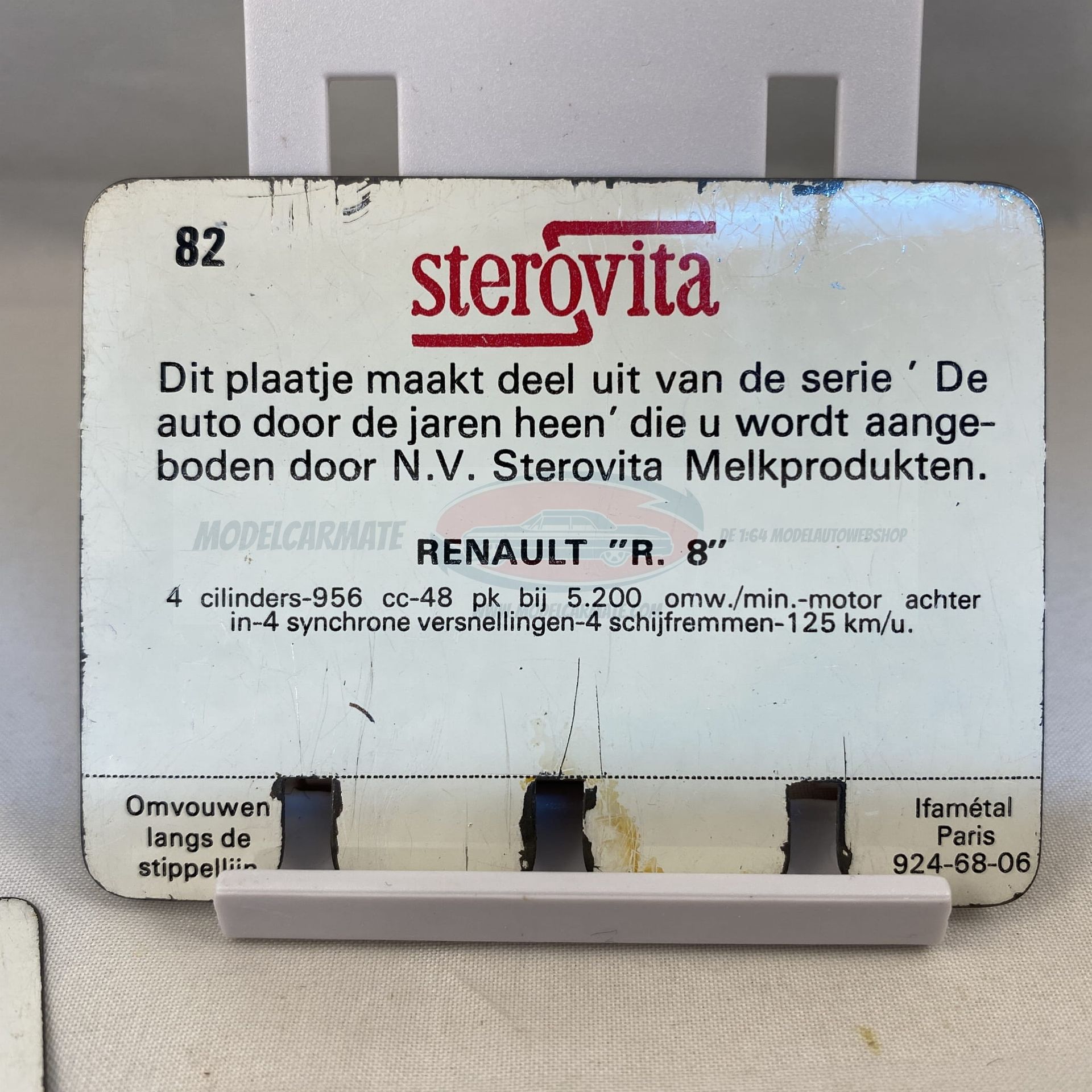 Een gele klassieke auto op een reclamekaart; op de achtergrond zijn een man te paard en een gebouw te zien.