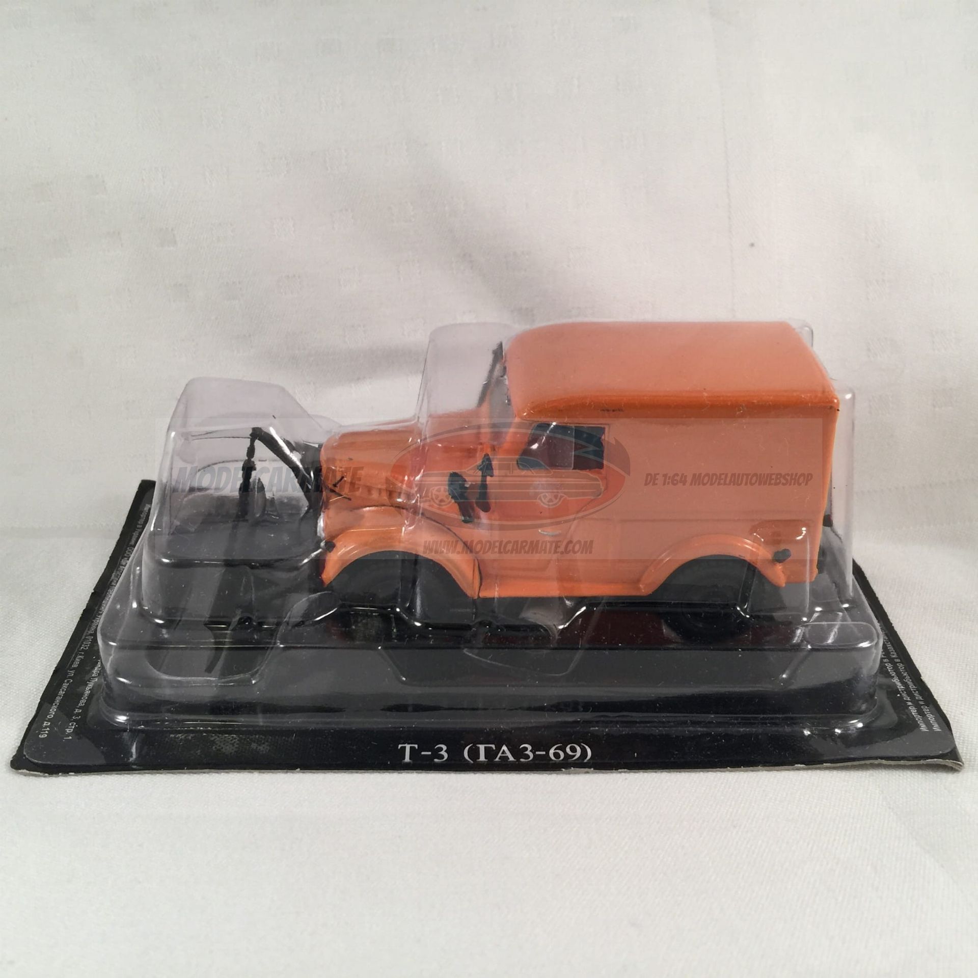 Oranje speelgoedtruck in plastic verpakking op een zwarte ondergrond.