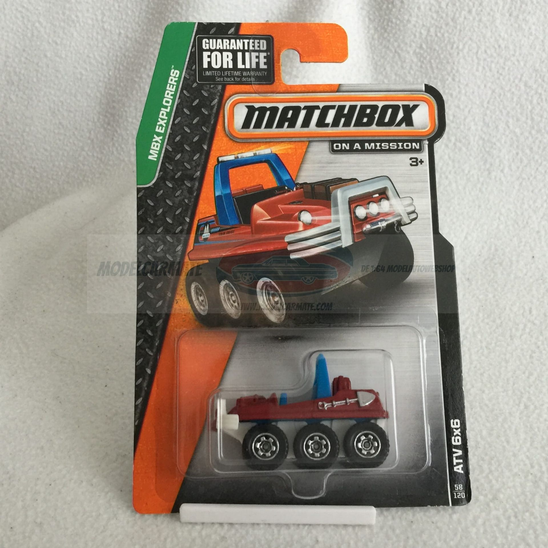 Matchbox speelgoedauto op een kaart: rode quad met zes wielen, blauwe rolbeugel en witte bumper.
